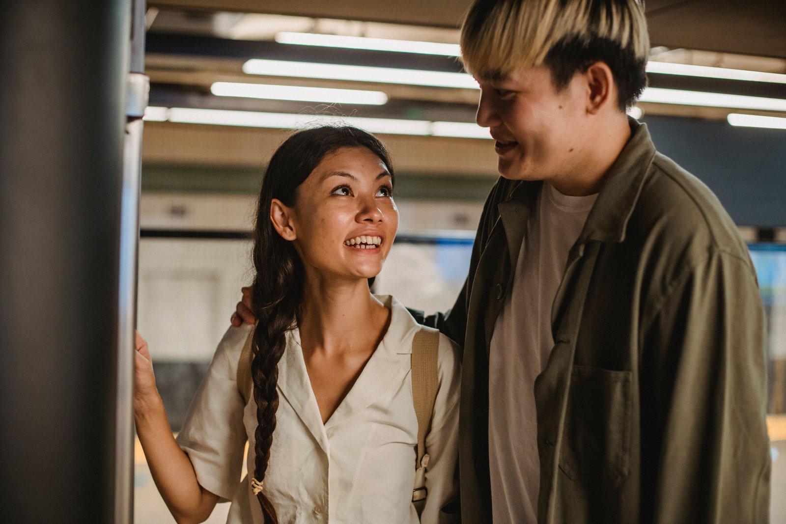Happy smiling Asian couple hugging and standing together in underground passage and looking at each other